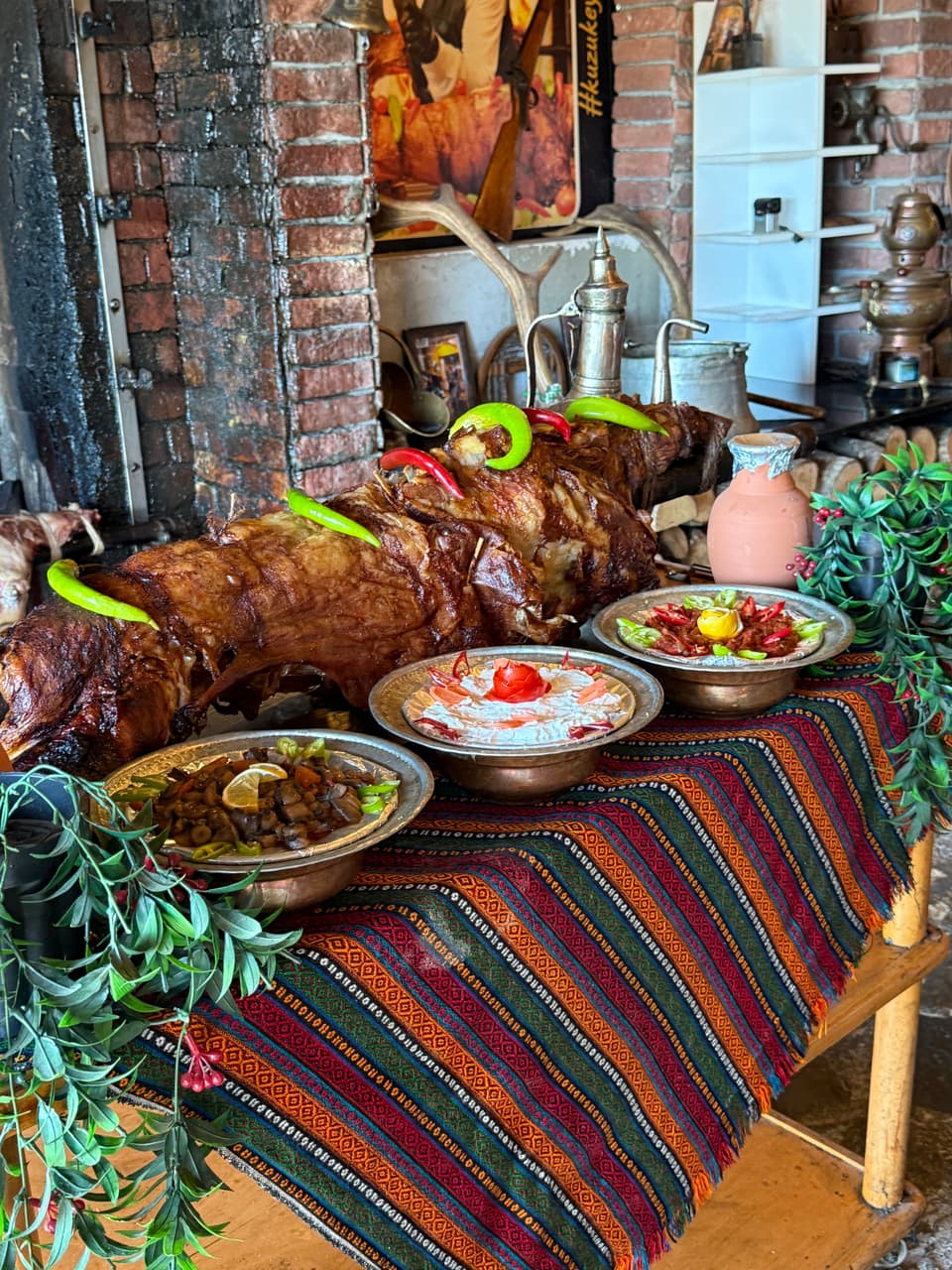 Kilim örtülü sunum masasında kuzu çevirme ve mezeler