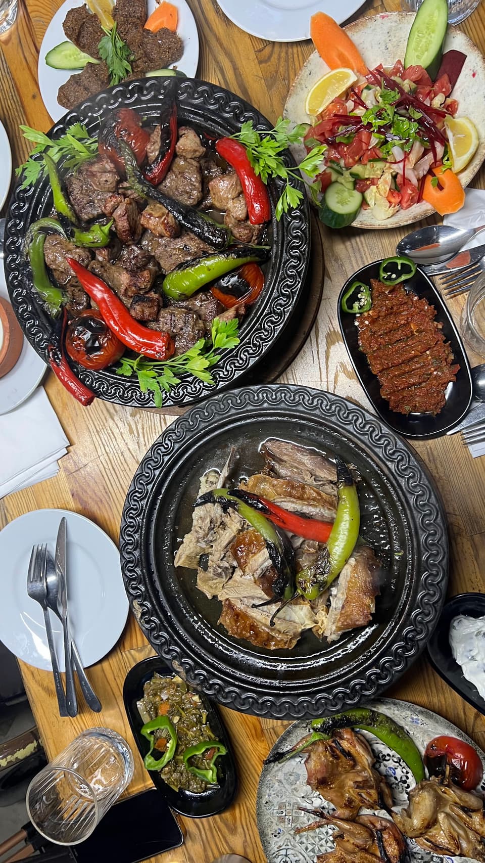 Döküm tabaklarda et yemekleri ve mezelerle kurulmuş sofra, üstten görünüm
